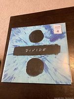 Front cover of the Ed Sheeran Divide double vinyl LP showing the blue tie-dye design with black division symbol and album title.