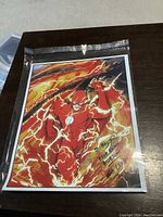 Photo of original Flash drawing in protective plastic sleeve showing vibrant colors and dynamic lightning effects.