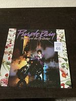 Front cover of Prince Purple Rain LP record album showing Prince seated on motorcycle under purple title text.