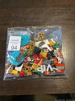 Sealed clear plastic bag with assorted LEGO pieces including VIP printed tiles, colorful bricks, and specialty parts for Lunar New Year theme.