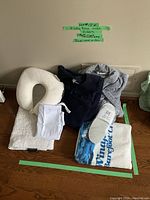 Photo of 2 ladies robes—navy and gray, white slippers, travel neck pillow, white bath mat, laundry bag, and beach towel on wood floor