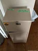 Closed beige metal lock box with a latch lock on top and a lower lockable cabinet door.