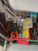 Photo showing assorted hand tools including wire strippers, pliers, hacksaw, and measuring square.
