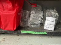 Photo showing multiple clear acrylic pamphlet display holders stacked and packaged with a handwritten label indicating 'Pamphlet Displays approx 50'.