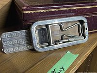 Photo of the metal foldable Rolls Razor out of its case, showing wear and the original leather pouch and metal components.