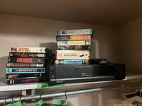 Sony Hi-Fi stereo VCR with remote and 14 assorted VHS tapes stacked around and on top of the VCR unit.