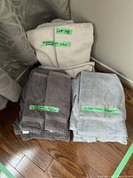 Photo showing three towel sets neatly stacked on the floor, labeled with green stickers indicating quantities per color group.