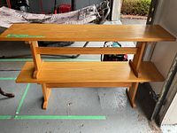 Two wooden benches stacked in garage, showing clean finish and simple rectangular form with lower shelf