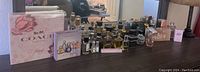 Wide view of perfume collection on a dresser with Coach Floral box and Estee Lauder box prominently visible along with multiple unboxed perfume bottles behind.
