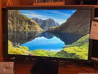 Front view of Dell curved monitor with screen on showing landscape image and time