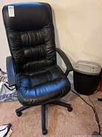 Side view showing black leather office chair and paper shredder beside it