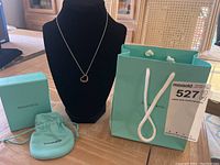 Necklace displayed on black bust with Tiffany & Co. box, pouch, and shopping bag