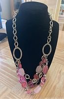 Photo shows a double-strand necklace with large oval silver links and assorted pink and translucent beads in varying shapes and sizes.