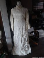 Full front view of the vintage 1950s ivory brocade wedding gown, showing high neckline, long sleeves, and full-length skirt.