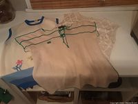 Three 1950s knit sweater tops arranged on a flat surface showing colors and designs.