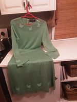 Full view of the sweater and skirt set displayed together showing color, length and butterfly accents.