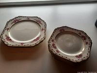 Stacked view of eight square sandwich plates with floral and gold trim pattern