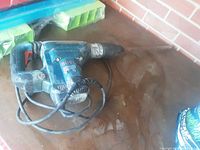 Bosch blue electric jackhammer showing the side view, cord coiled around the tool with visible wear and paint scuffs.