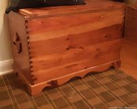 Side view of the chest showing carved maple leaf handle, dovetail joints, and base design.