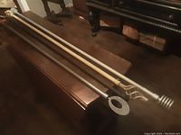 Top view of five curtain rods laid horizontally showing variety of finials and finishes.