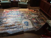 Photo showing three large graffiti wallpaper mural panels laid out on the floor among living room furniture, panels display vibrant colorful graffiti artwork on front side.