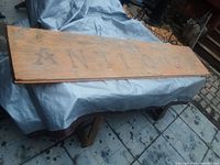 Large wooden sign with visible fading and wood grain, spelling out 'ANTIQUES' faintly.