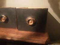 Close-up of the front black painted exterior of one wooden drawer showing the round knob and wear marks.