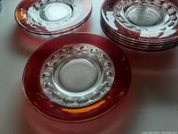 Stacked ruby glass sandwich plates showing clear center and thick ruby red rim with bubble pattern.