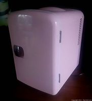Closed view of compact pink travel fridge showing smooth exterior and chrome latch handle.