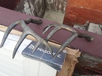 Pair of dark composite antlers, showing their overall shape and size, placed on a box labeled 'Masonite'.