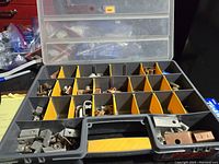 Top view of open carrying case showing multiple compartments with assorted metal electrical connectors and fittings inside.