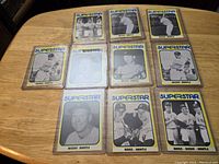 10 vintage Mickey Mantle and related baseball cards laid out on a table in protective cases, showing front images with 'Superstar' label.