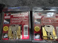 Two new Husky trailer coupler locks in original packaging, gold zinc molded lock bodies with two keys each, packaging shows bilingual text and product details.