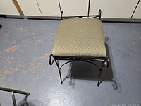 Top view of decorative foot stool showing green upholstery and metal frame legs and decorative scroll detail