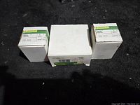 Three boxed Greenlee hole saws placed on black surface showing front of boxes.