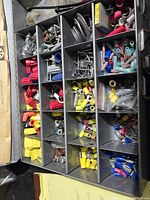 Overview of the metal compartmentalized box showing multiple compartments with colorful wire connectors, metal terminals, screws, and cable ties.