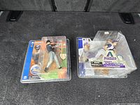 Photo showing two McFarlane MLB Hall of Fame collectible figures, Mike Piazza and Randy Johnson, in sealed packaging.