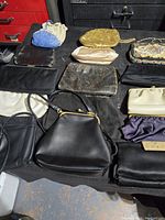 Photo of 15 vintage purses and clutches arranged on a black surface showing varied colors, materials and styles.