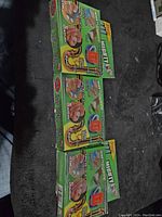 Front view of three stacked green boxes of Mighty Putty kits showing usage images and branding.