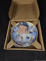 Collector plate of Mickey Mantle in packaging, showing the plate protected in a cardboard holder and wrapped in plastic.