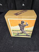 Cardboard box with Monument Park Collection logo and a baseball stadium illustration with a batter silhouette