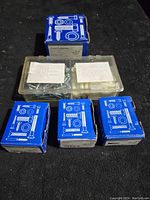 Five boxes containing wall anchors and screws placed on a black surface.