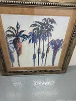 Framed vintage palm tree print showing artistic palm tree images with mat and heavy carved wood frame.