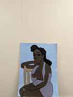 Original draft painting on paper pinned to a wall showing a stylized seated woman with dark skin and black hair in a white garment sitting on a wooden chair with a blue background.