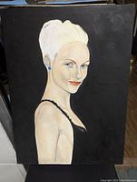 Frontal photo of the painting showing the woman in a half-length portrait with platinum blonde hair, light skin tone, blue eyes, and red lipstick against a black background.