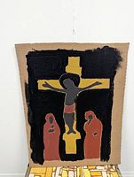 Photo showing the full painting with a black background, yellow cross, and three reddish human figures on recycled cardboard.