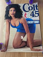 Full view of the vintage Colt 45 promotional poster featuring a woman in a blue dress kneeling with the slogan "EVERY TIME!" and the Colt 45 logo.