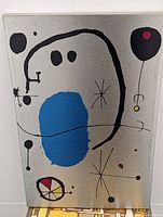 Front view of the Joan Miro style canvas print showing abstract elements in black, blue, red and yellow on a silver background.