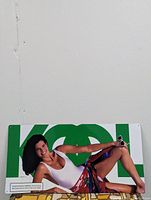 Full vintage Kool tin advertisement sign showing the model reclining with sunglasses and cigarette against green background letters.