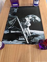 Photo showing the vintage astronaut on moon print on a wooden surface with surrounding objects for scale.